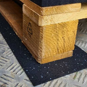 FitFloors.com Anti Slip Rubber Mat Confetti Underlayment For Floor Protection And Traction placed beneath a wooden pallet on a metal industrial floor for added traction and protection.