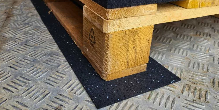 FitFloors.com Anti Slip Rubber Mat Confetti Underlayment For Floor Protection And Traction placed beneath a wooden pallet on a metal industrial floor for added traction and protection.