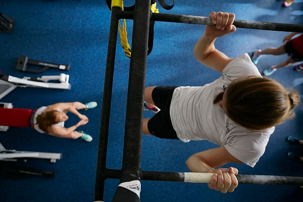 Galaxy Plus Rubber Gym Flooring Rolls - 48-Inch Wide, Recycled Rubber, Slip-Resistant, USA Made beneath athletes performing pull-ups in a training gym; rubber gym flooring rolls application