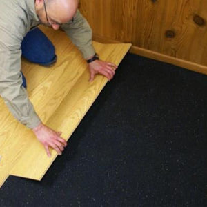 Rubber underlayment flooring roll being unrolled on subfloor during installation