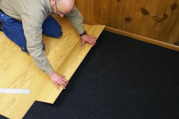Rubber underlayment flooring roll being unrolled on subfloor during installation